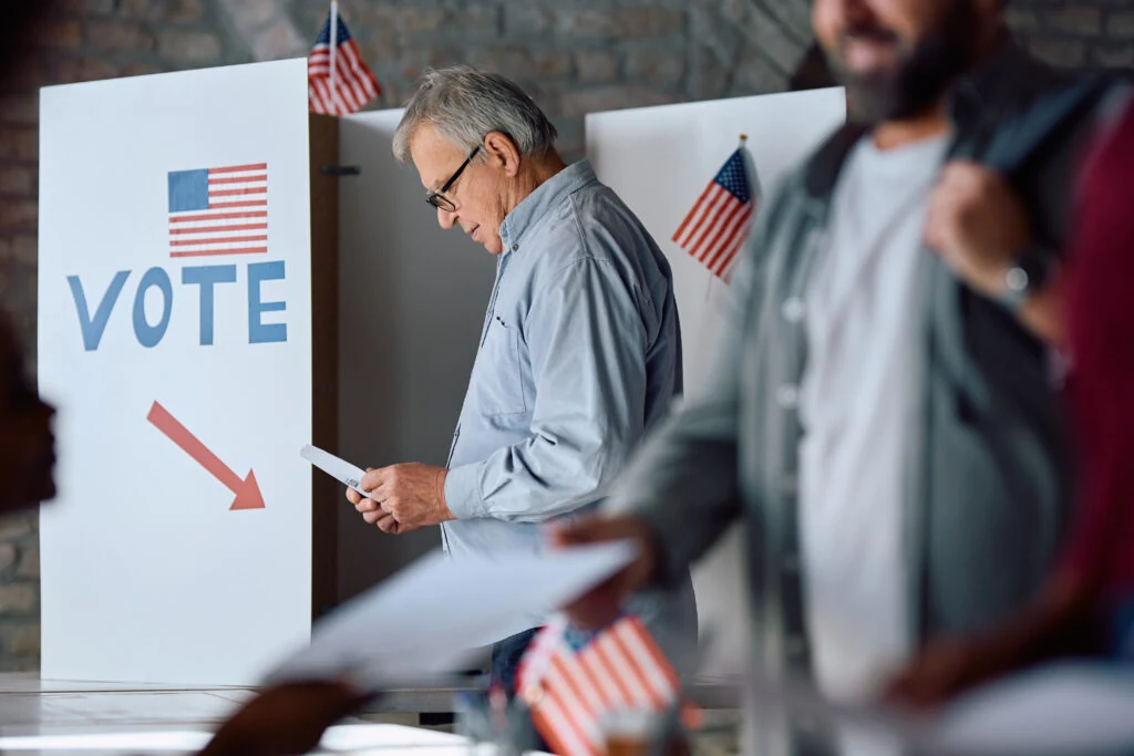A man filling in his ballot at a voting booth